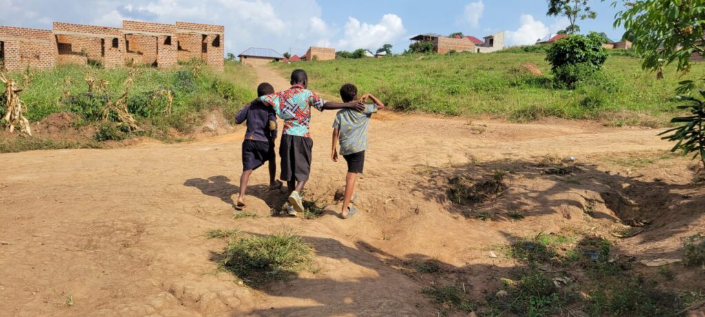 dirt road, three boys walking, village in Uganda